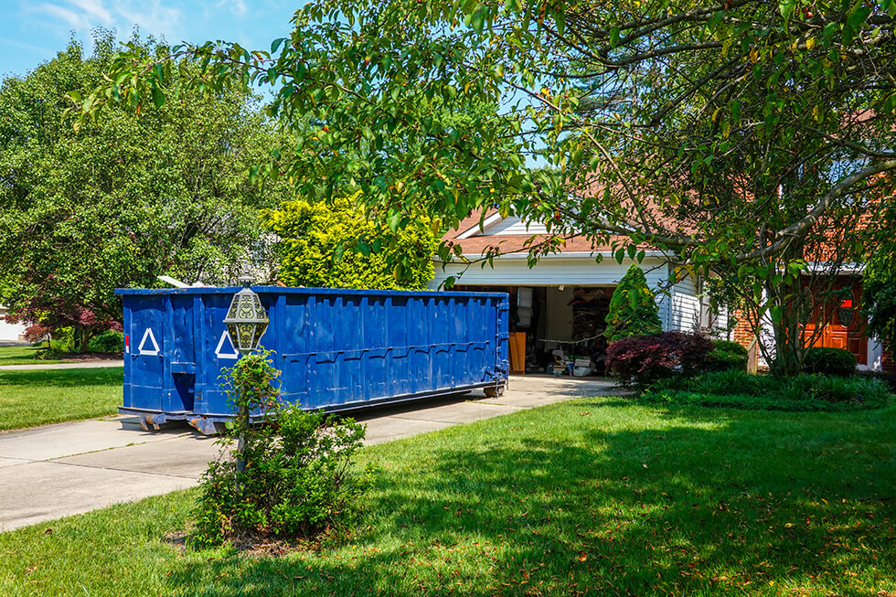 blue dumpster in the driveway